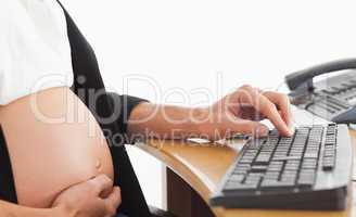 Pregnant woman on the phone working with a computer