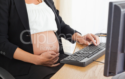 Young pregnant woman on the phone working with a computer