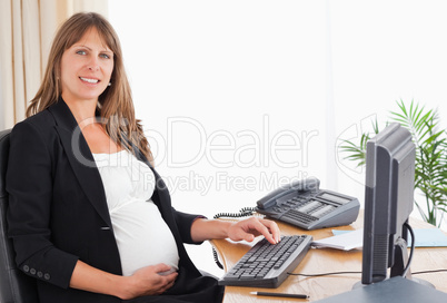 Gorgeous pregnant woman working with a computer