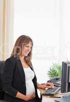 Attractive pregnant female working with a computer