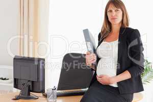 Good looking pregnant female holding a file while standing