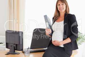 Pretty pregnant female holding a file while standing