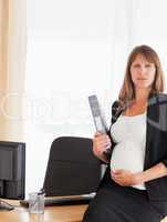 Lovely pregnant female holding a file while standing