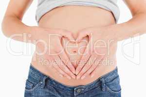 Close-up of a young pregnant female posing while forming a heart