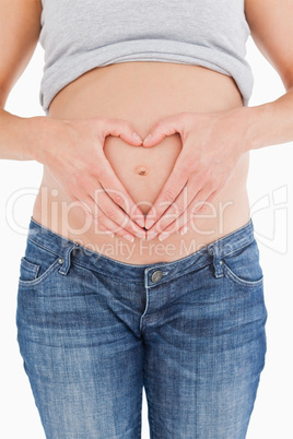 Close-up of a pregnant female posing while forming a heart with