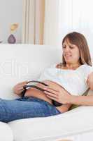 Portrait of a pregnant woman with headphones on her tummy