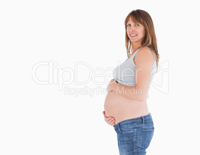 Side view of a beautiful pregnant woman caressing her belly whil