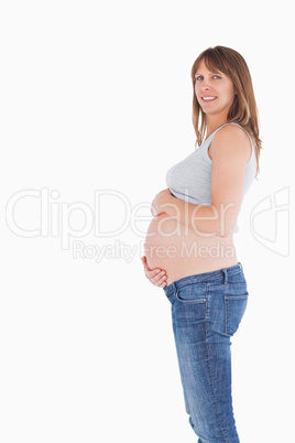 Side view of a good looking pregnant woman caressing her belly w