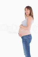 Side view of a good looking pregnant woman caressing her belly w