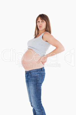 Beautiful pregnant woman holding her back while standing Beautiful pregnant woman holding her back while standing