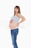 Attractive pregnant woman holding her back while standing