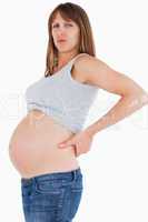 Good looking pregnant woman holding her back while standing