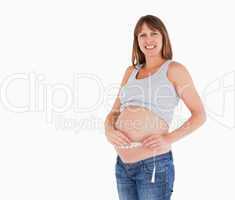 Pretty pregnant woman measuring her belly while standing