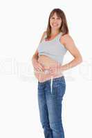Good loooking pregnant woman measuring her belly while standing