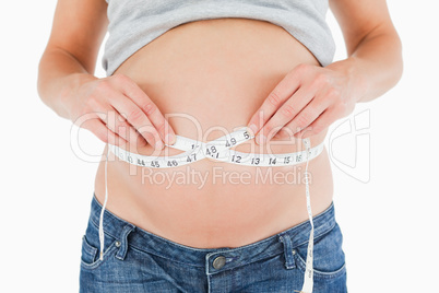 Young pregnant woman measuring her belly while standing