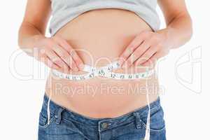 Young pregnant woman measuring her belly while standing