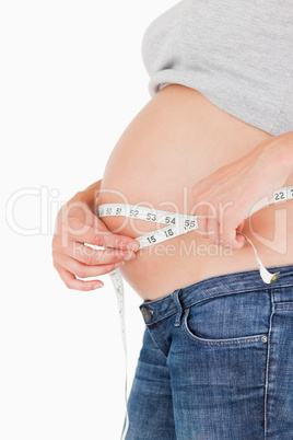 Pregnant woman measuring her belly while standing