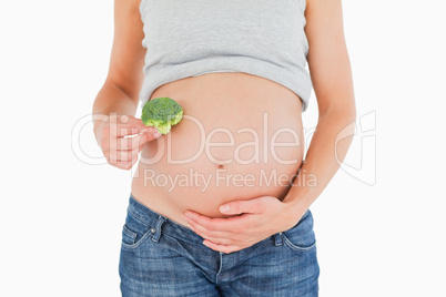 Pregnant woman holding a broccoli while standing