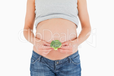 Young pregnant woman holding a broccoli while standing