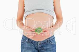 Young pregnant woman holding a broccoli while standing