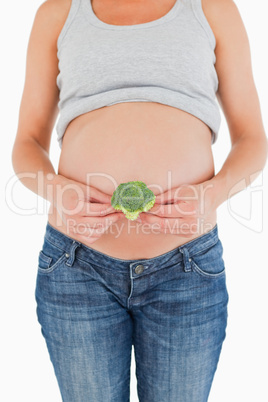 Pregnant woman holding a broccoli while standing