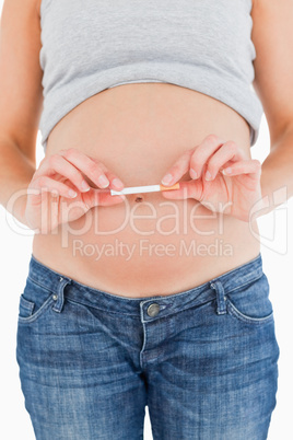 Young pregnant woman holding a cigarette while standing