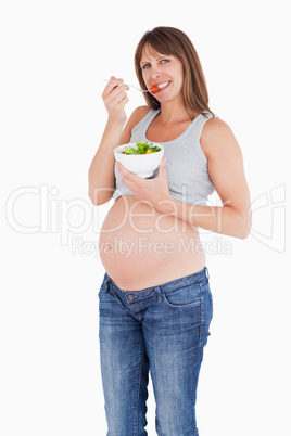 Attractive pregnant woman eating a cherry tomato while holding a