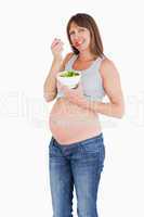 Attractive pregnant woman eating a cherry tomato while holding a