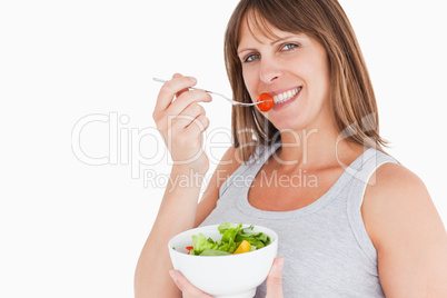 Good looking pregnant woman eating a cherry tomato while holding