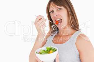 Pretty pregnant woman eating a cherry tomato while holding a bow