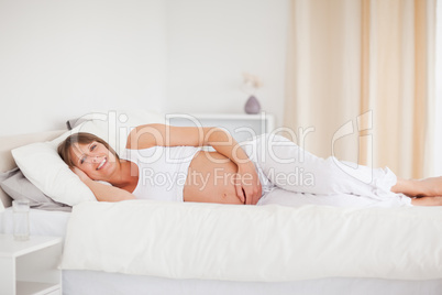 Attractive pregnant woman relaxing while lying on her bed