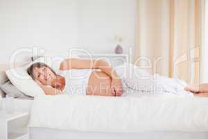 Attractive pregnant woman relaxing while lying on her bed