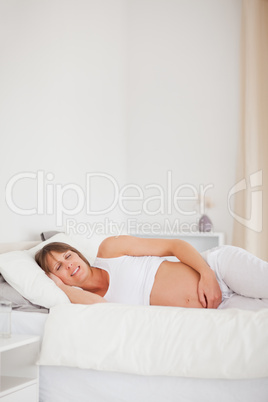 Pretty pregnant woman relaxing while lying on her bed