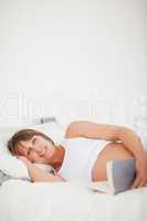 Charming pregnant woman reading a book while lying on her bed