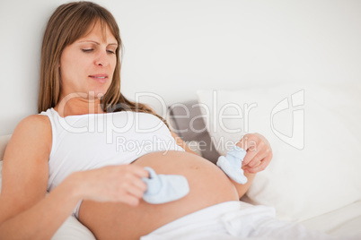 Good looking pregnant woman playing with little socks while lyin