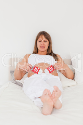 Good looking pregnant female playing with little red shoes while