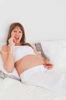 Good looking pregnant female eating some strawberries while lyin