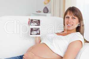 Happy pregnant woman showing her baby's ultrasound scan