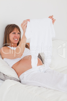 Attractive pregnant female showing a little white pyjama while l