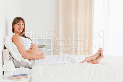 Portrait of a good looking pregnant female posing while lying on