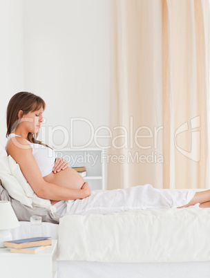 Portrait of a gorgeous pregnant female lying on a bed