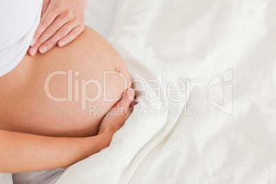 Close-up of a young pregnant female lying on a bed