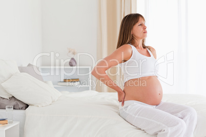 Beautiful pregnant female having a back pain while sitting on a