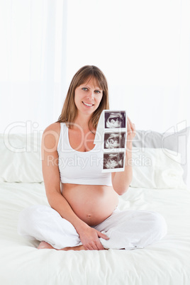 Attractive pregnant female showing an ultrasound scan while sitt