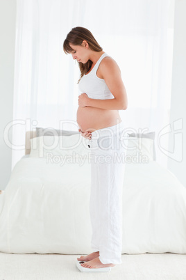 Attractive pregnant female using a scale while standing