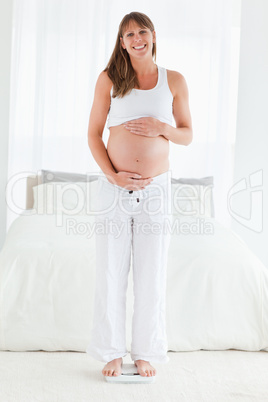 Beautiful pregnant female using a scale while standing