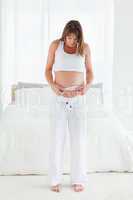 Attractive pregnant female using a tape measure while standing