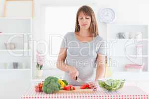 Attractive pregnant woman posing while cooking vegetables