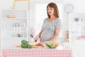 Lovely pregnant woman posing while cooking vegetables