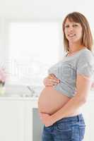 Beautiful pregnant woman posing while caressing her belly